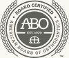 Board-certified ABO seal in grayscale with ornamental laurel border and text reading “American Board of Optometry”
