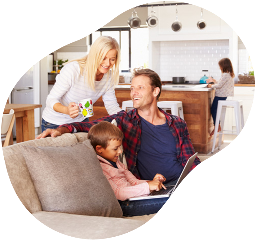 Family relaxing in a bright living room, with one person handing a card to a man holding a child.