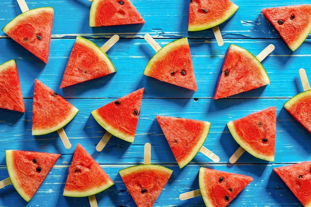 Watermelon slices on blue wooden boards, arranged like colorful popsicle treats