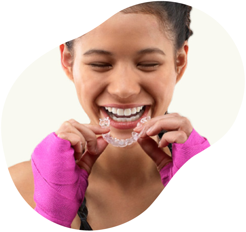 Woman smiling while putting in clear dental aligners with both hands