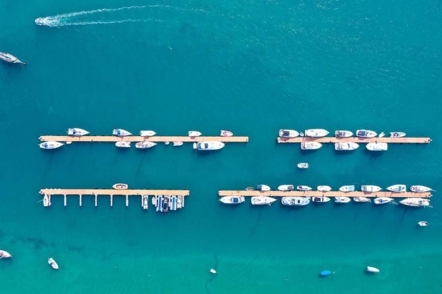 Aerial view of a marina with multiple piers and docked boats in turquoise water.