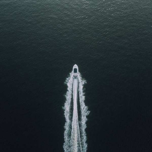 Boat moving across dark water, creating a white wake.
