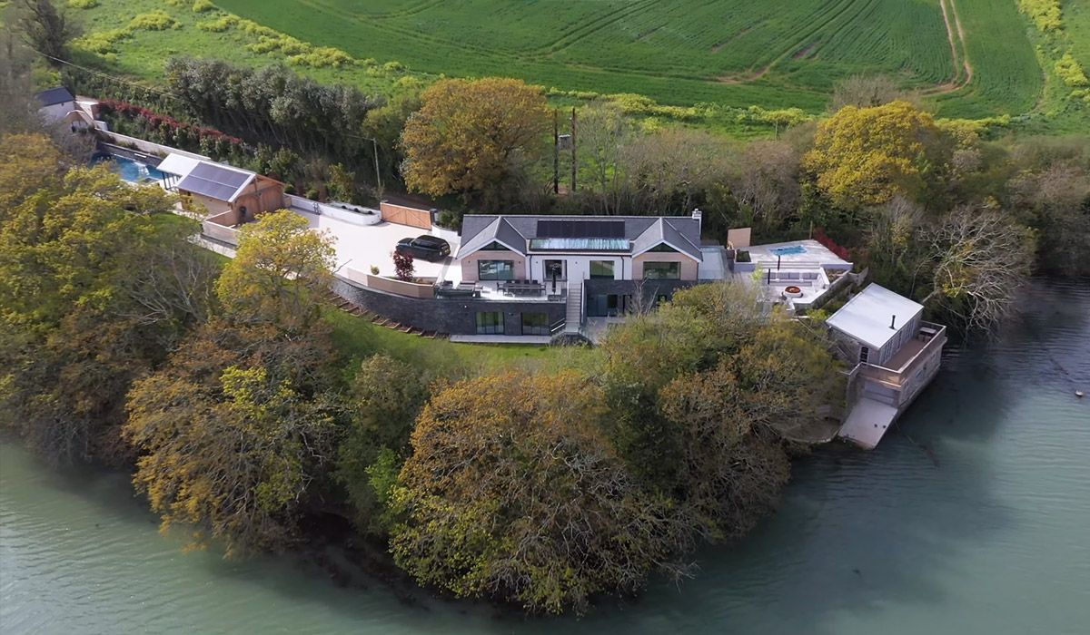 Large house with water access, surrounded by trees and a green field.