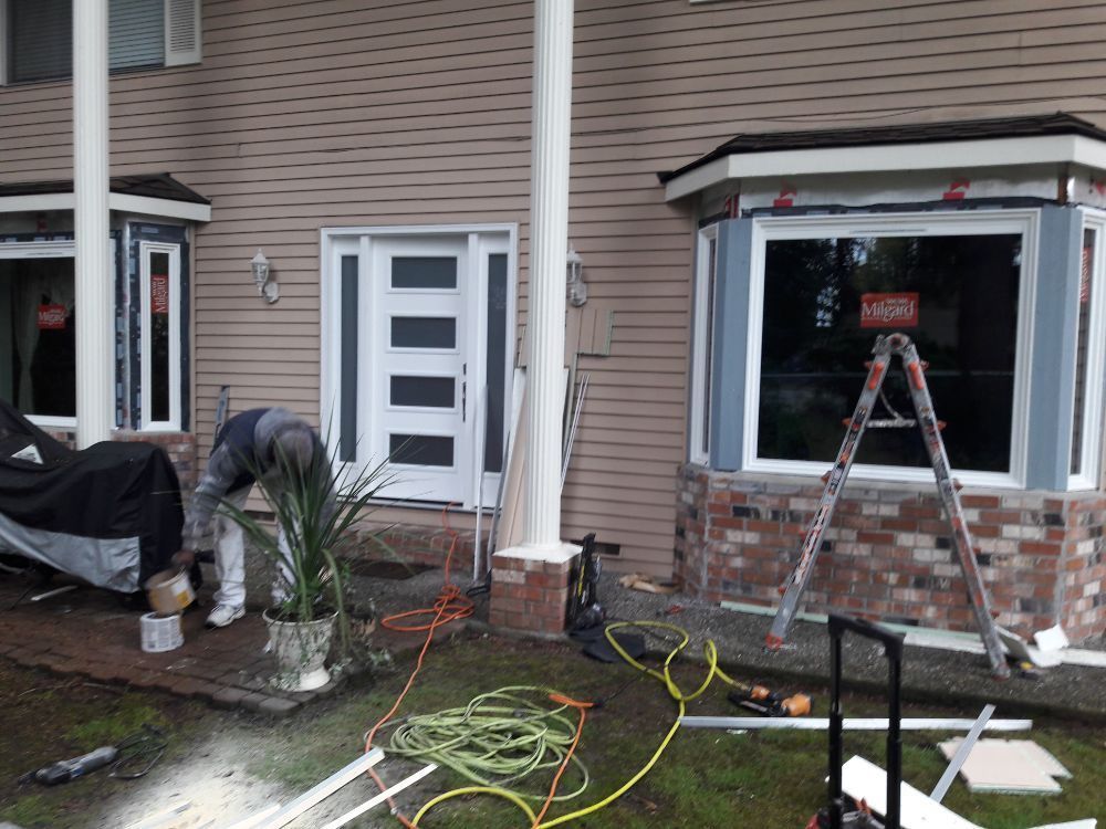 A man is working on a window on the front of a house.
