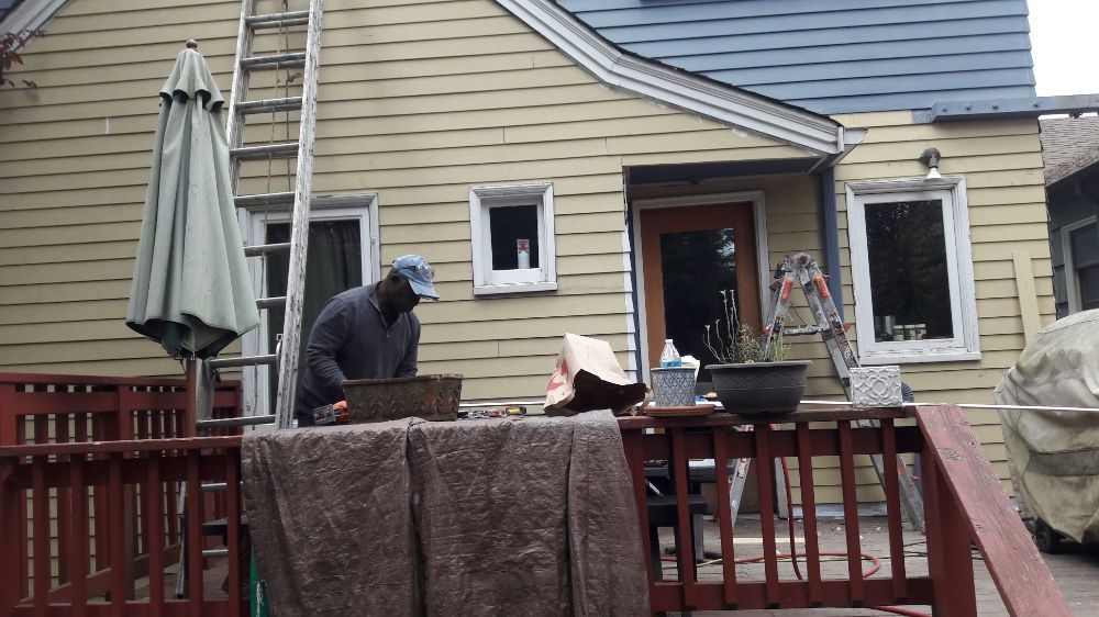 A man is standing on a deck in front of a house.