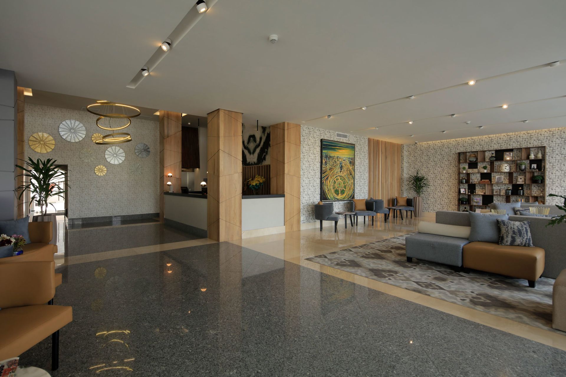 Vestíbulo de hotel moderno con cómodos sillones, iluminación cálida, suelo de mármol y obras de arte decorativas.
