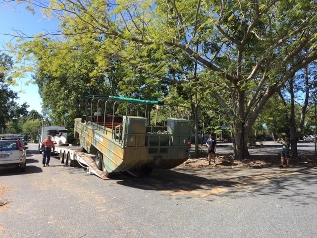 A Large Military Vehicle is on a Trailer in a Parking Lot — Kelly's Crane Hire in Mossman, QLD