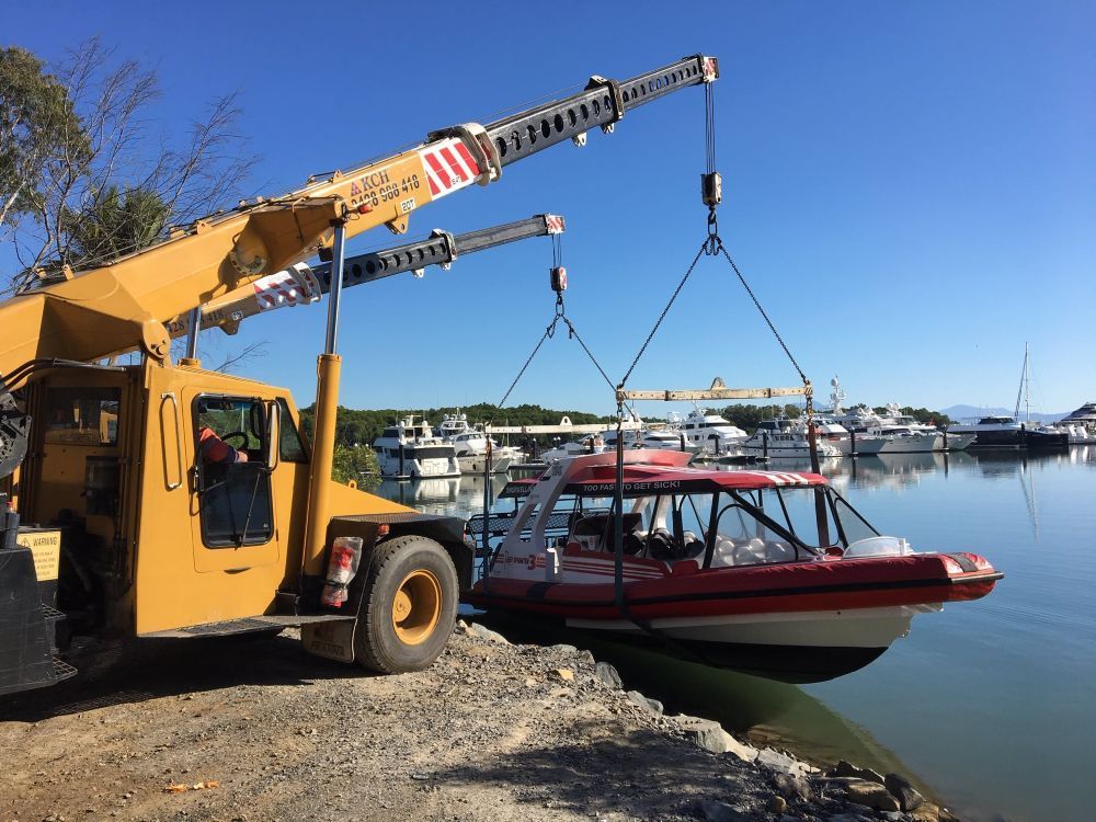 A Crane is Lifting a Boat Into the Water — Kelly's Crane Hire in Mossman, QLD