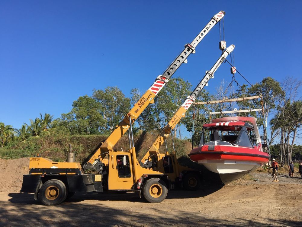 A Crane is Lifting a Boat Into the Water — Kelly's Crane Hire in Mossman, QLD