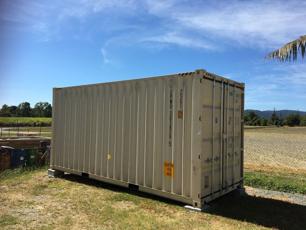 A Shipping Container is Parked in a Grassy Field — Kelly's Crane Hire in Mossman, QLD