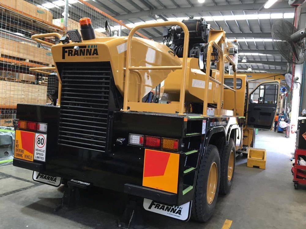 A Yellow Truck With the Word Franna on the Back is Parked in a Warehouse — Kelly's Crane Hire in Mossman, QLD