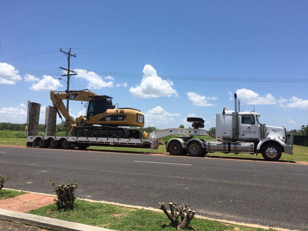 A Semi Truck is Carrying a Bulldozer Down a Road — Kelly's Crane Hire in Mossman, QLD