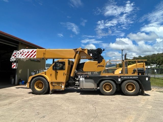 A Large Yellow Crane is Parked in Front of a Building — Kelly's Crane Hire in Mossman, QLD