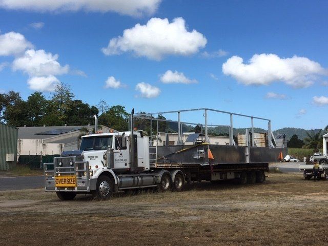 A Semi Truck With a Trailer Attached to It is Parked in a Field — Kelly's Crane Hire in Mossman, QLD