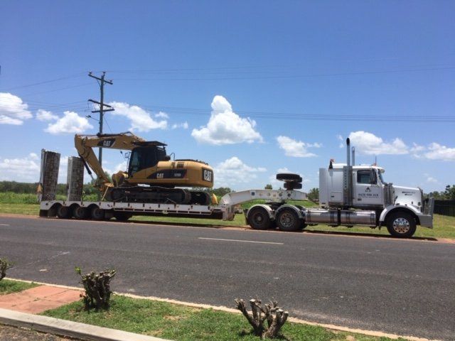 A Semi Truck is Carrying an Excavator Down a Road — Kelly's Crane Hire in Mossman, QLD