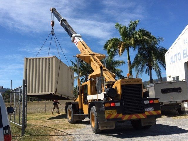 A Crane is Lifting a Container in a Parking Lot — Kelly's Crane Hire in Mossman, QLD