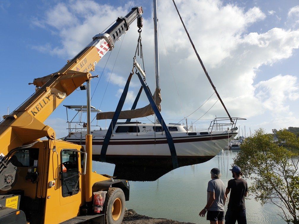 A Crane is Lifting a Boat Into the Water — Kelly's Crane Hire in Mossman, QLD