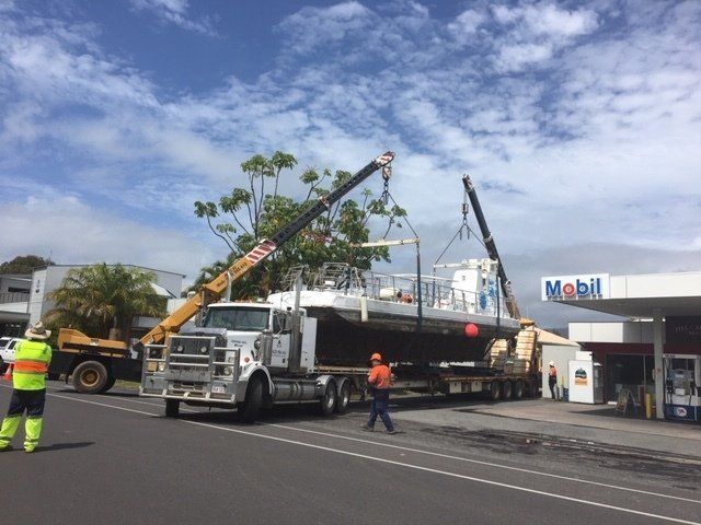 A Boat is Being Lifted by a Crane on a Trailer — Kelly's Crane Hire in Mossman, QLD