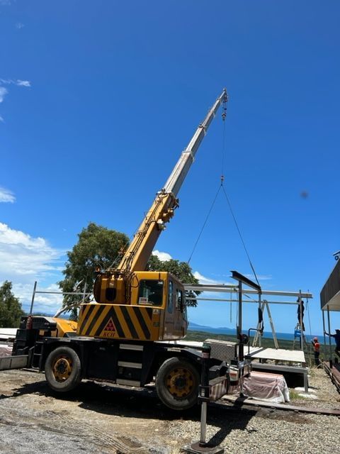 A Man is Driving a Forklift in a Grassy Field — Kelly's Crane Hire in Mossman, QLD