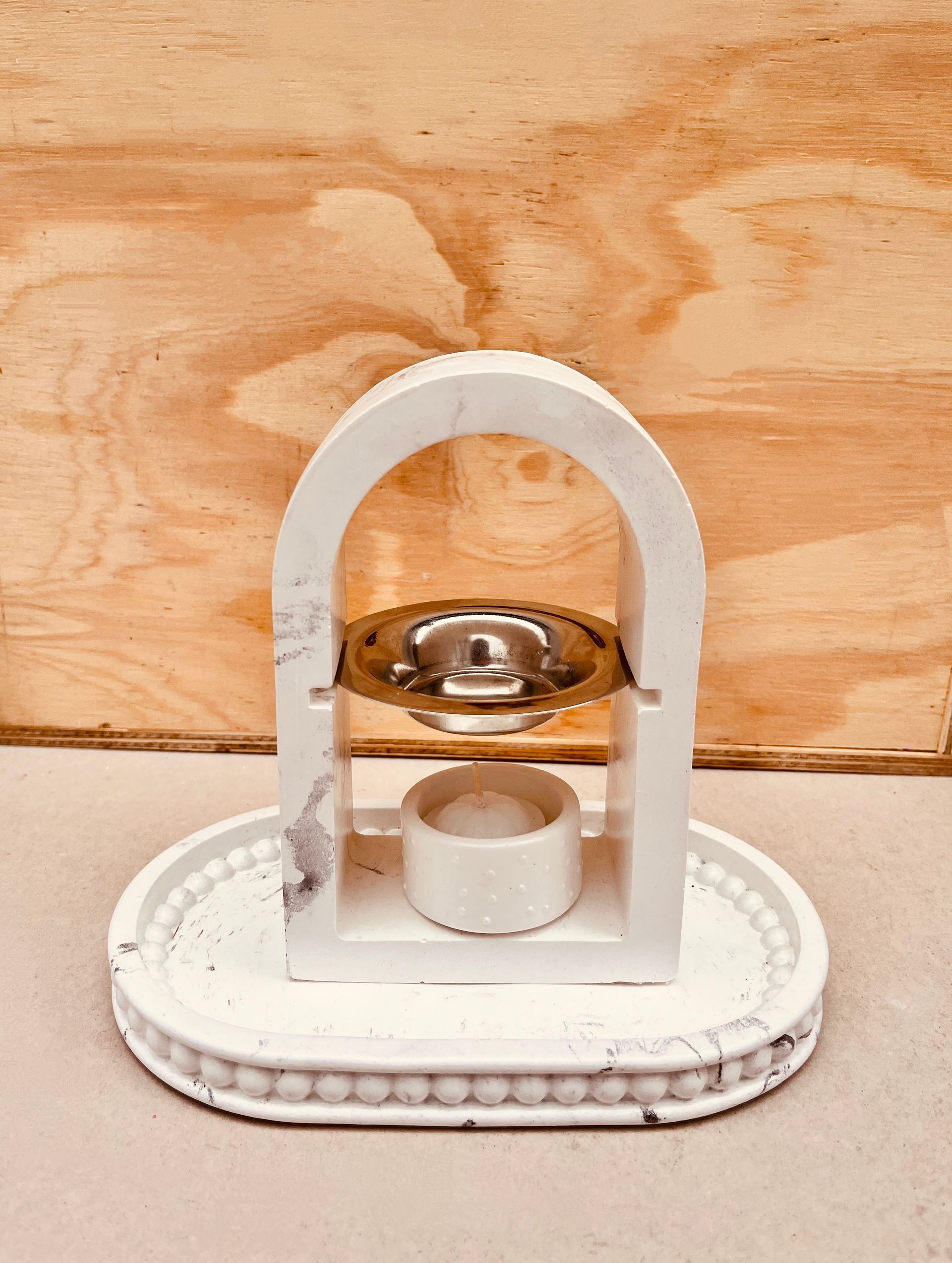 Pequeño dispositivo de sobremesa blanco y dorado sobre una base ovalada con fondo de madera.