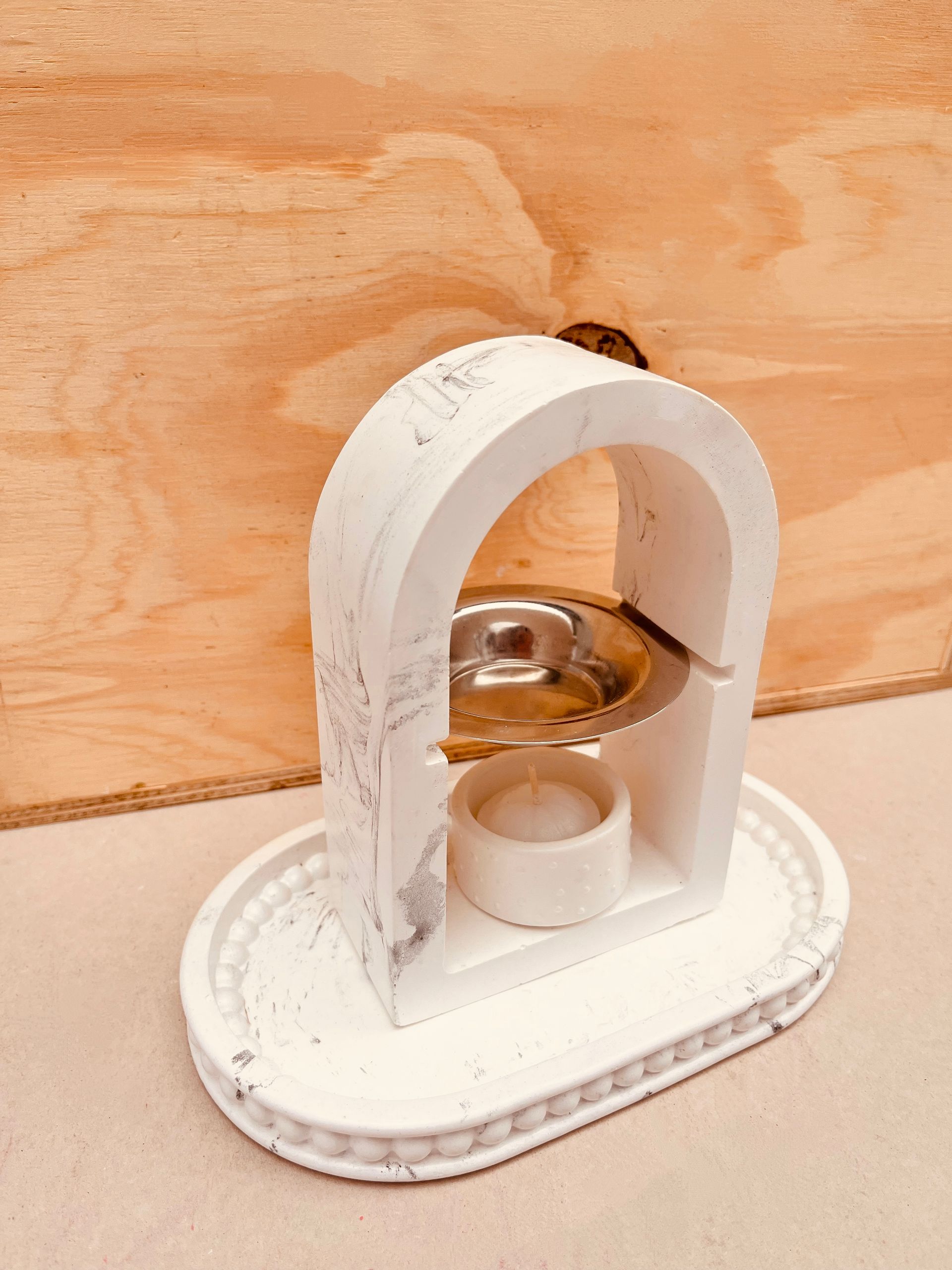 Pequeño dispositivo de sobremesa blanco y dorado sobre una base ovalada con fondo de madera.