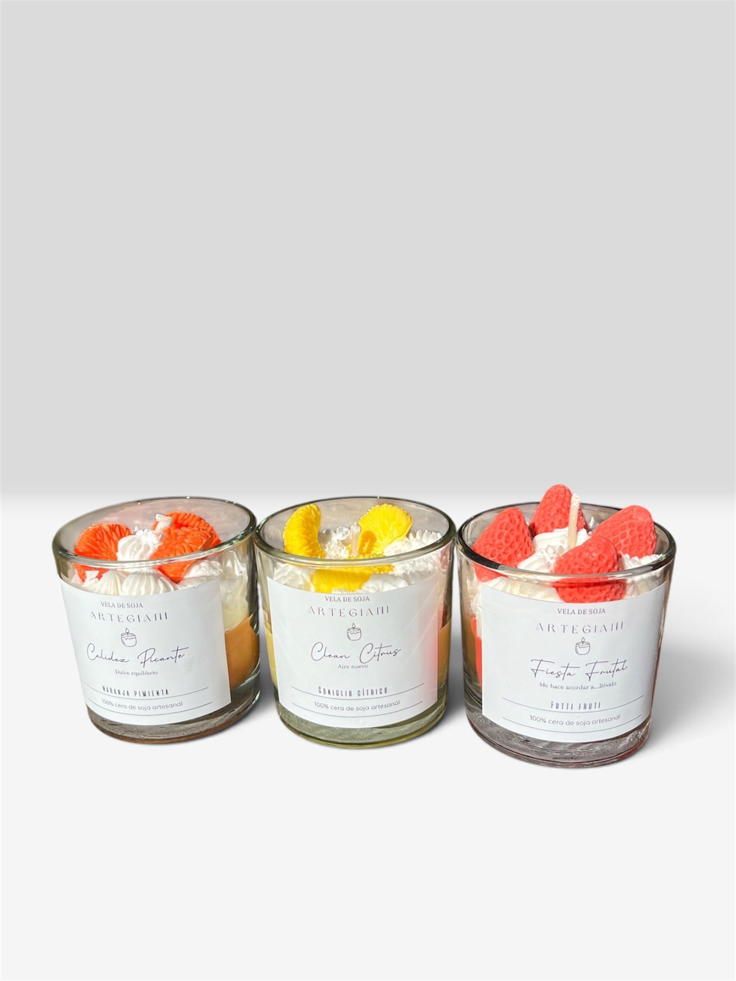 Tres tarros de postre cubiertos con nata montada y fruta sobre una superficie blanca.
