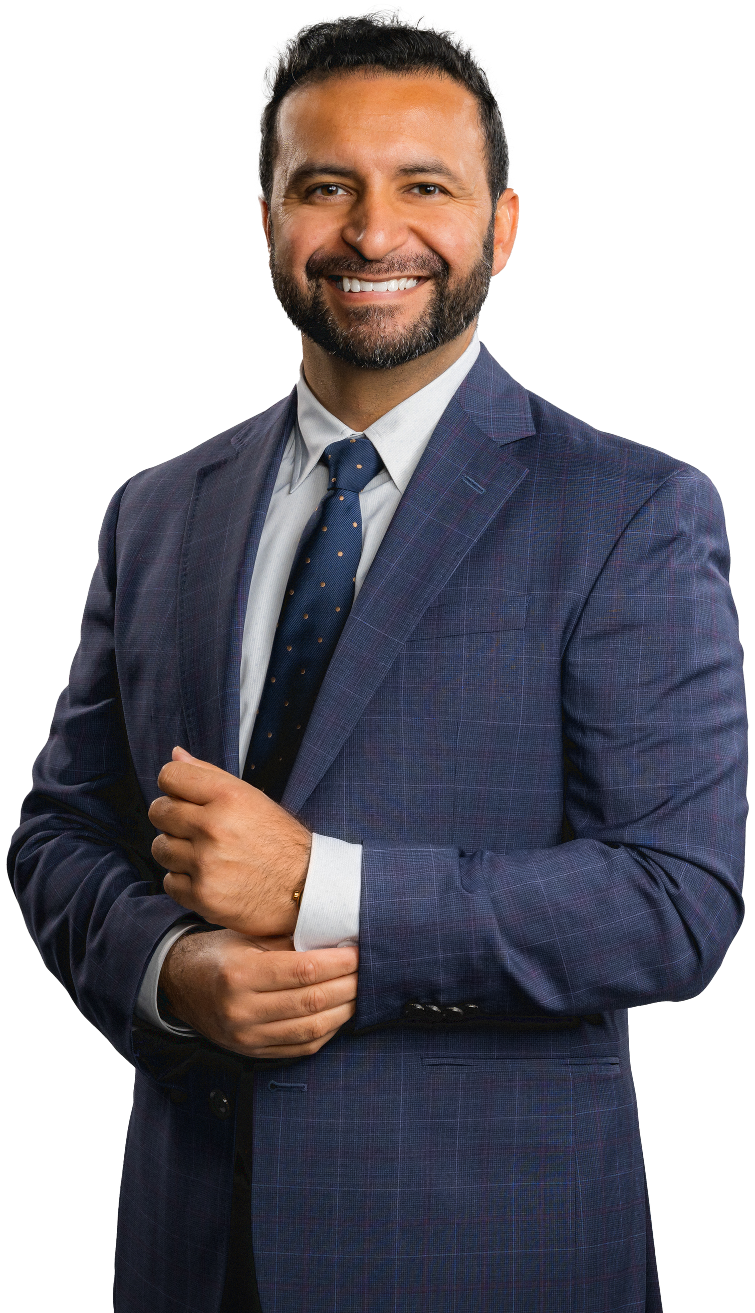 A man in a suit and tie is standing with his hands folded.