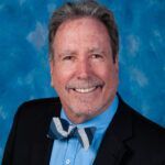 A man in a suit and bow tie is smiling for the camera.