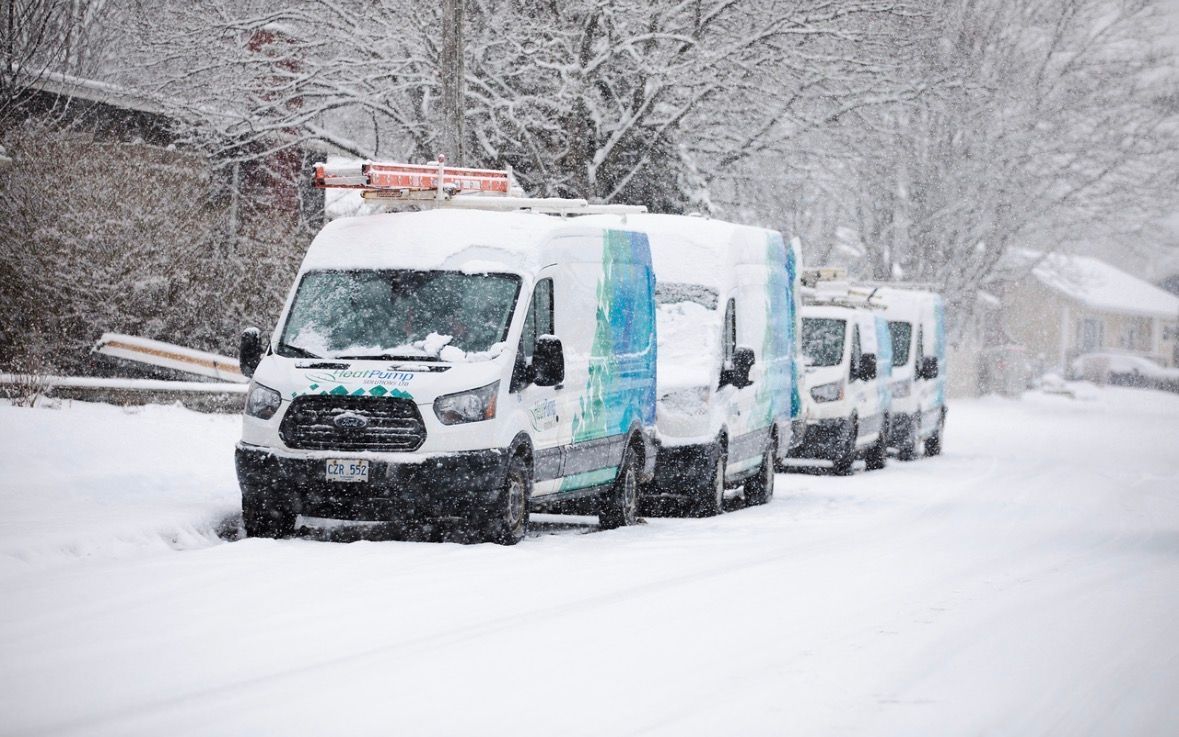 Snow-covered utility vans parked on a snowy road in a winter storm