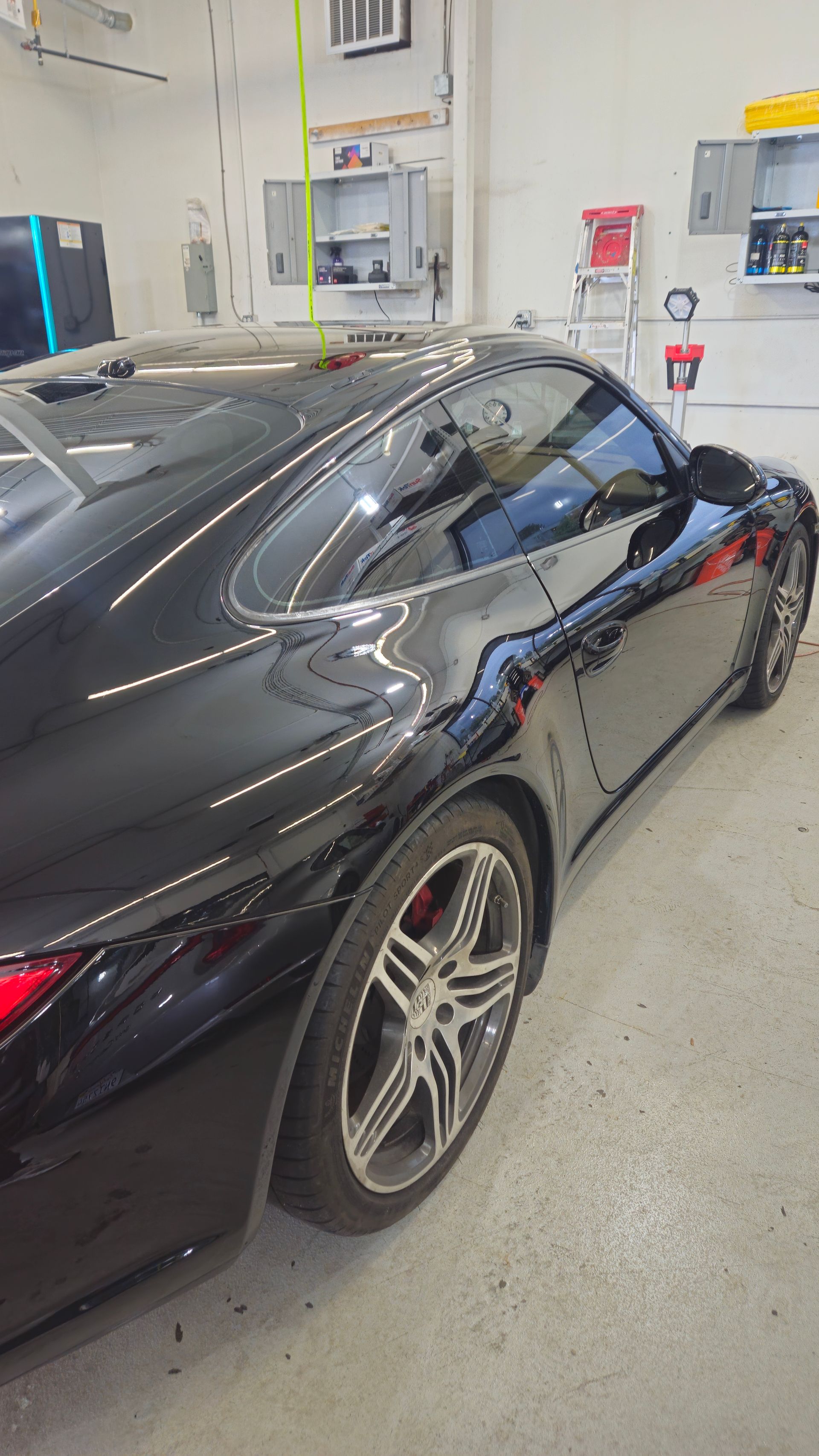 Black Porsche sports car with tinted windows in a garage.