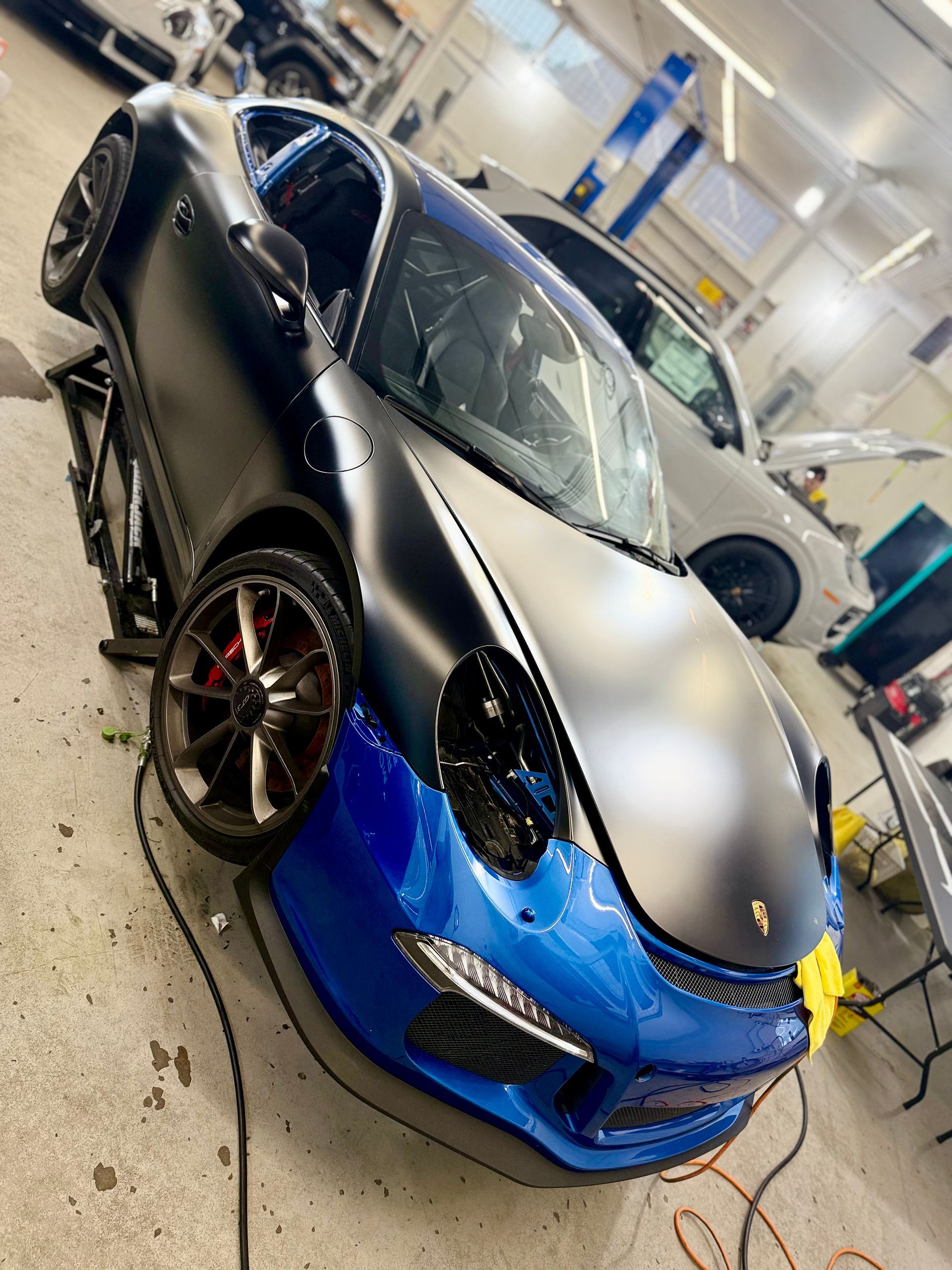 A black and blue Porsche being worked on in a garage.