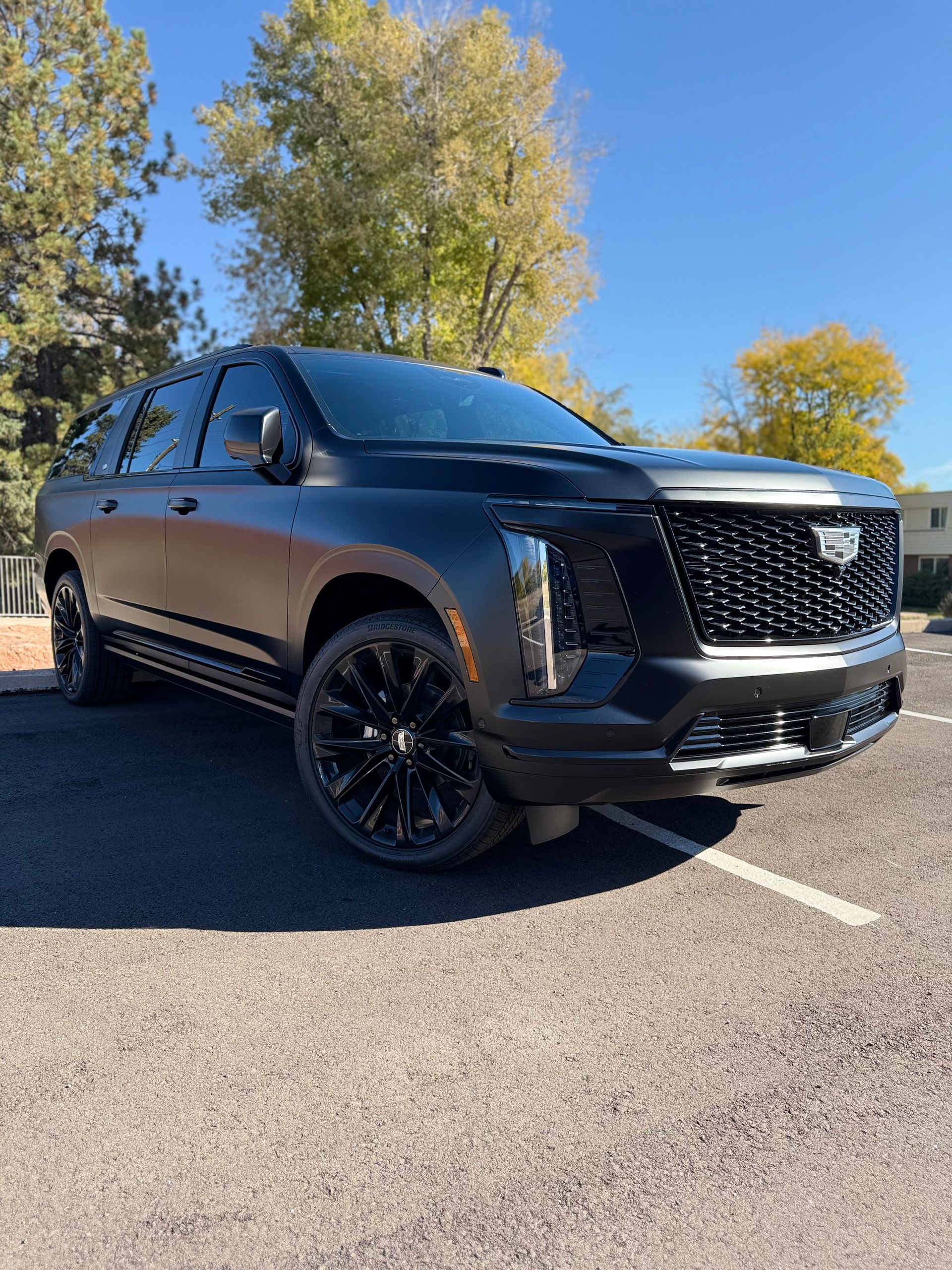 Black Cadillac Escalade SUV parked outside on a sunny day.