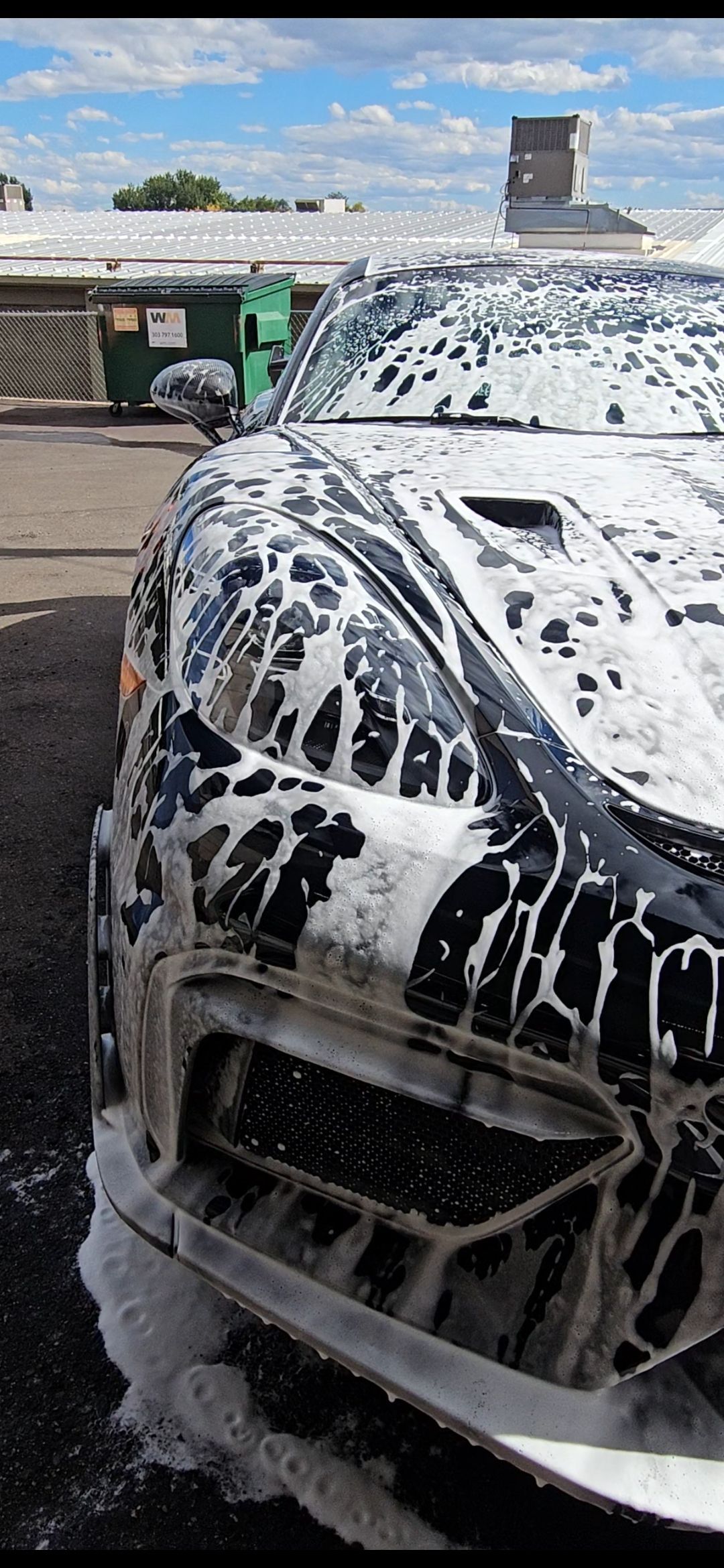 Black car covered in foamy soap at a car wash.