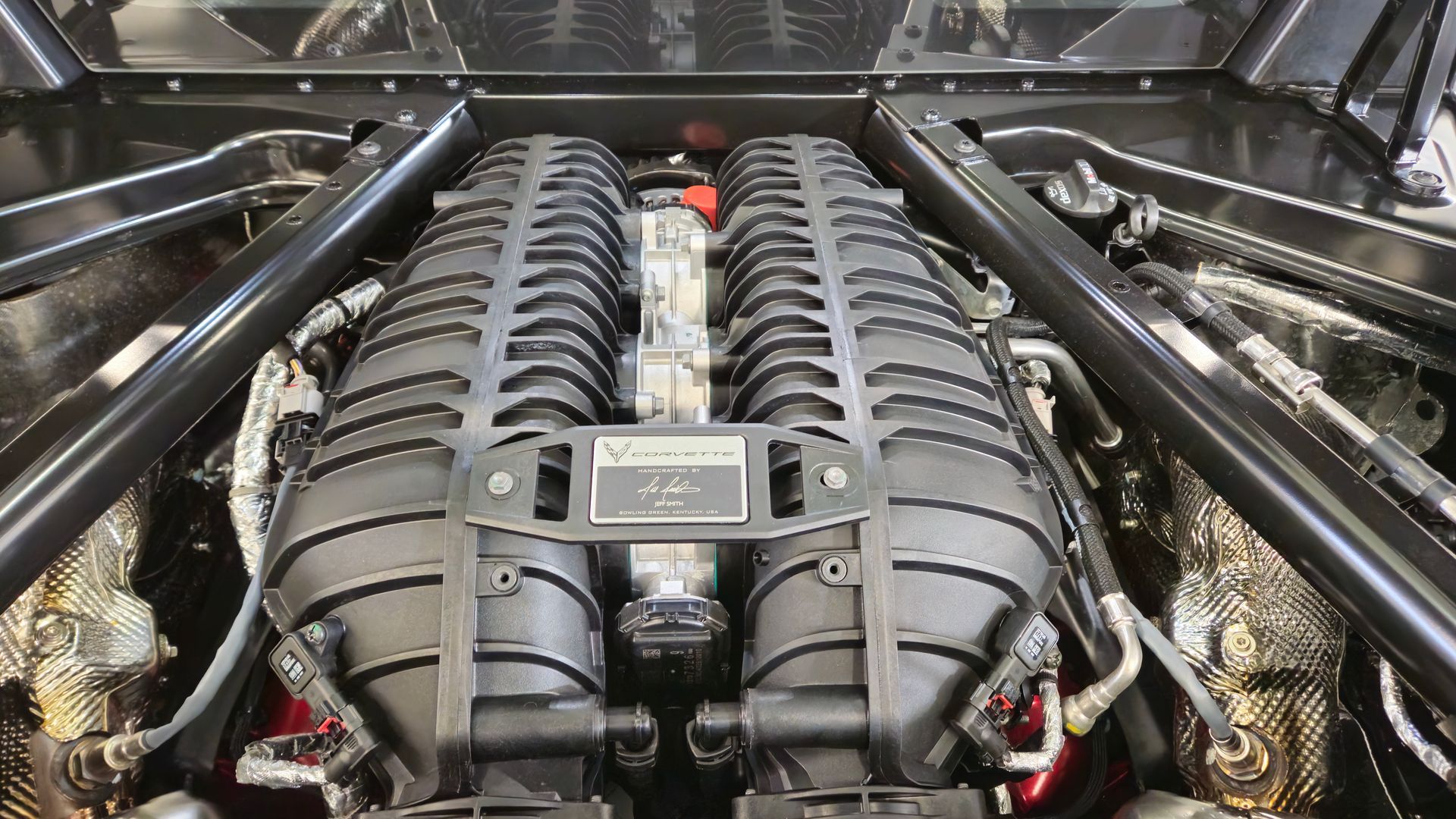 Close-up of a black engine compartment with two large, covered engine components and supporting beams.