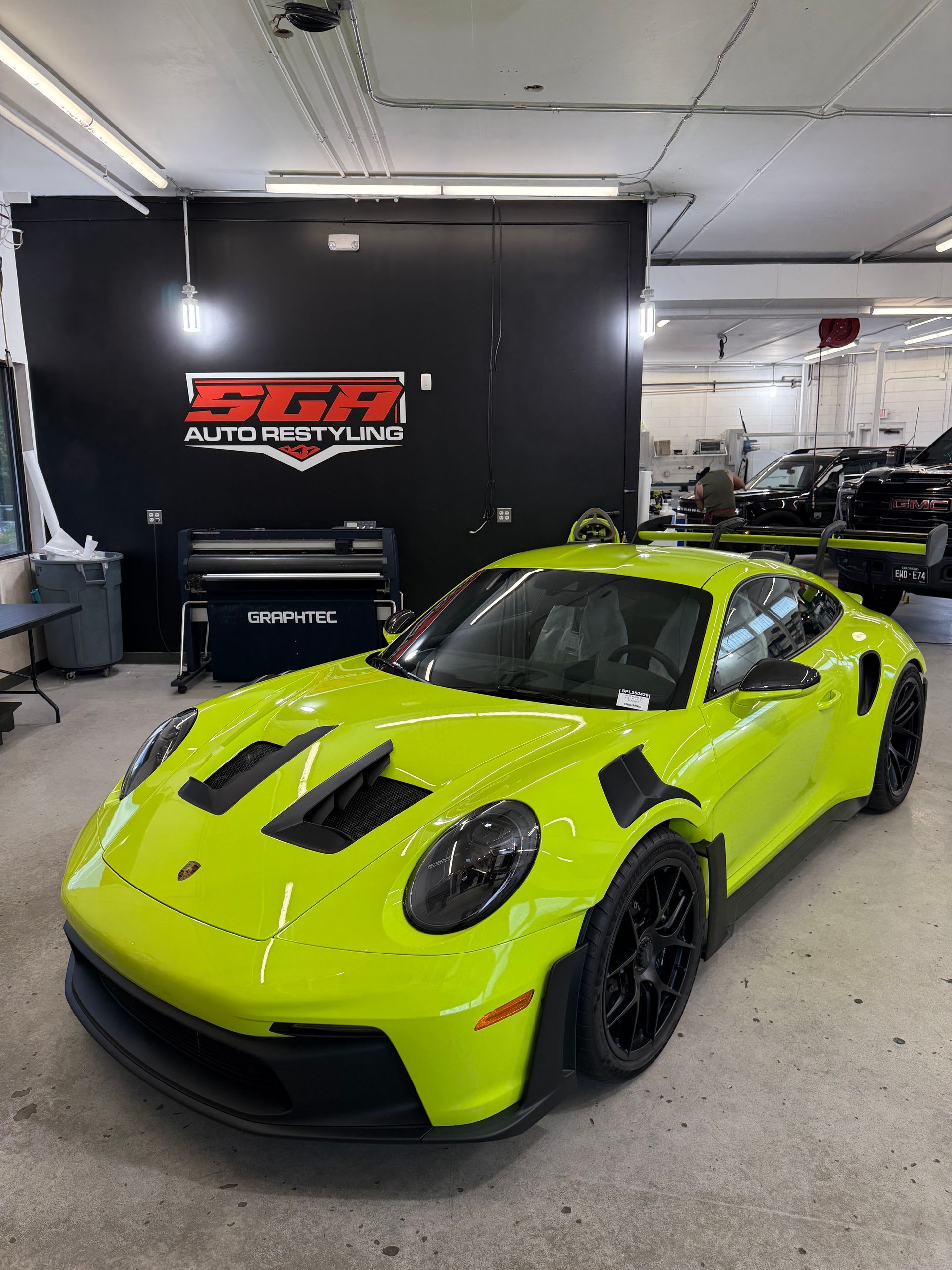 Bright green Porsche 911 GT3 RS parked inside a garage. Black wheels, black accents, and 