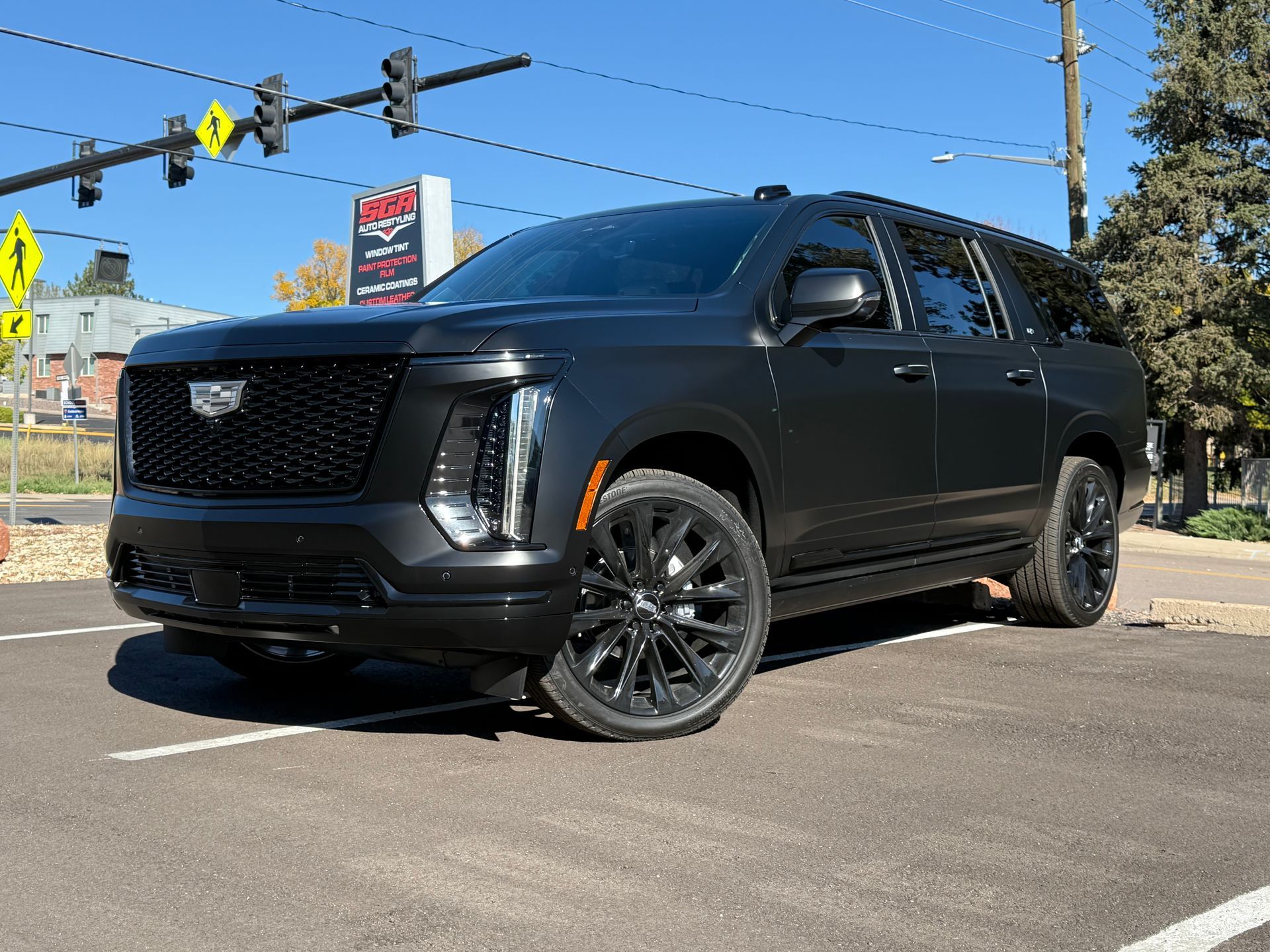Black Cadillac SUV with matte finish, parked inside a garage, with black wheels.