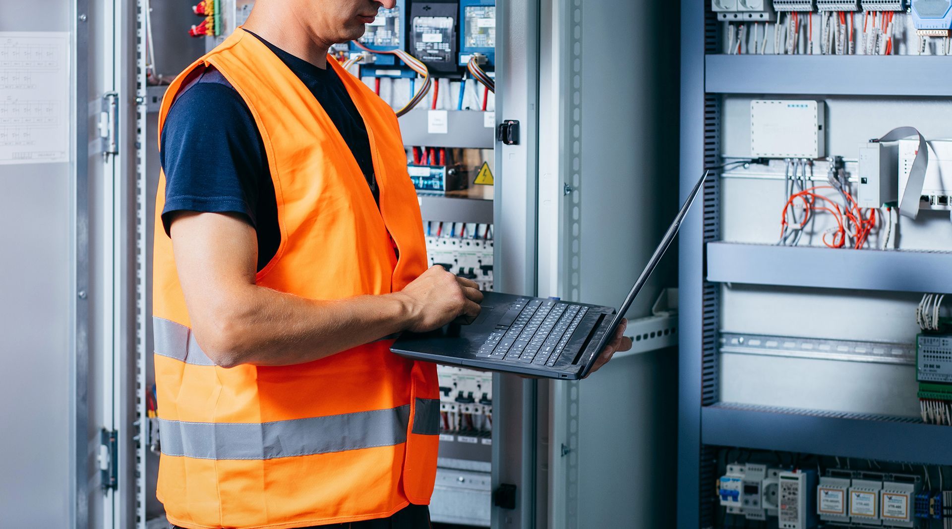 Electrician from Preferred Electric installing or repairing an electrical panel with wiring and tools in a residential or commercial setting.