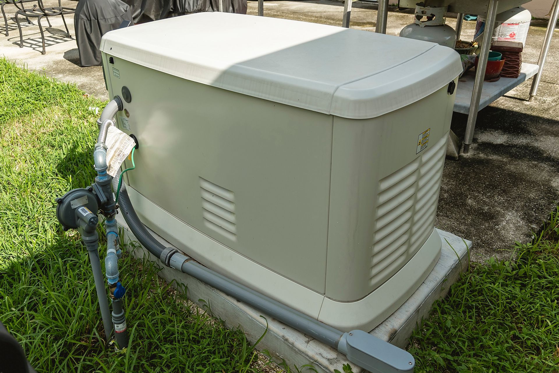 A generator is sitting on top of a concrete base in the grass