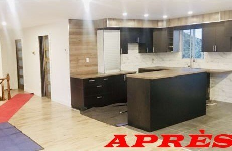 Rénovation de cuisine moderne : armoires foncées, comptoirs clairs, îlot, mur lambrissé de bois, aménagement ouvert. « APRÈS » en texte rouge.