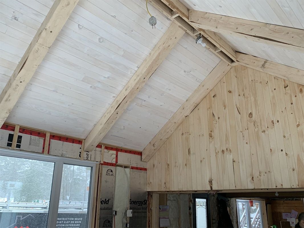 Vue intérieure d'un toit à ossature bois, avec des panneaux de bois sur les murs et le plafond.
