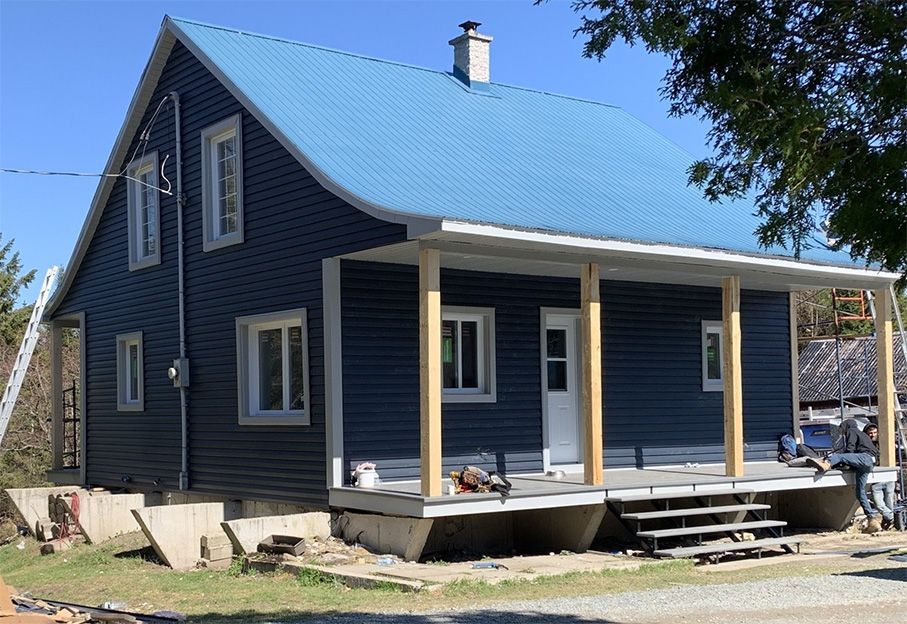 Maison bleue à deux étages avec un toit bleu et un porche en construction.