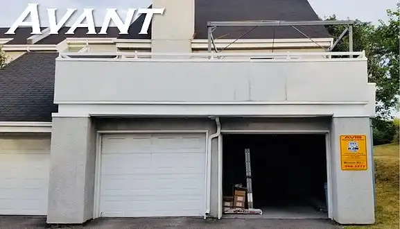 Extérieur du garage avec portes blanches et façade grise. Étiquette « AVANT » en haut.