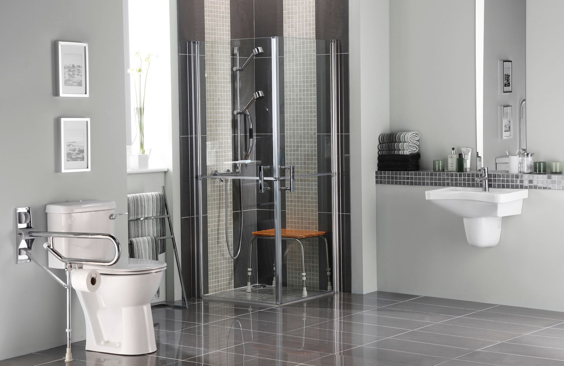 Accessible bathroom with toilet, shower, and sink; gray walls, chrome fixtures, and mosaic tile in shower.