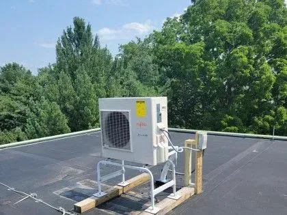Outdoor HVAC unit on a flat rooftop with trees in the background