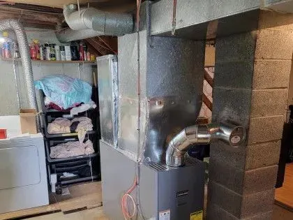 Basement utility room with furnace, ductwork, and a washer/dryer next to stacked storage shelves.