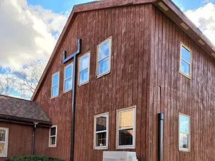 Red barn-style building with a large cross on the side under a cloudy sky