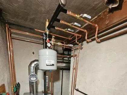 Basement utility room with water heater, pipes, and exposed ceiling plumbing