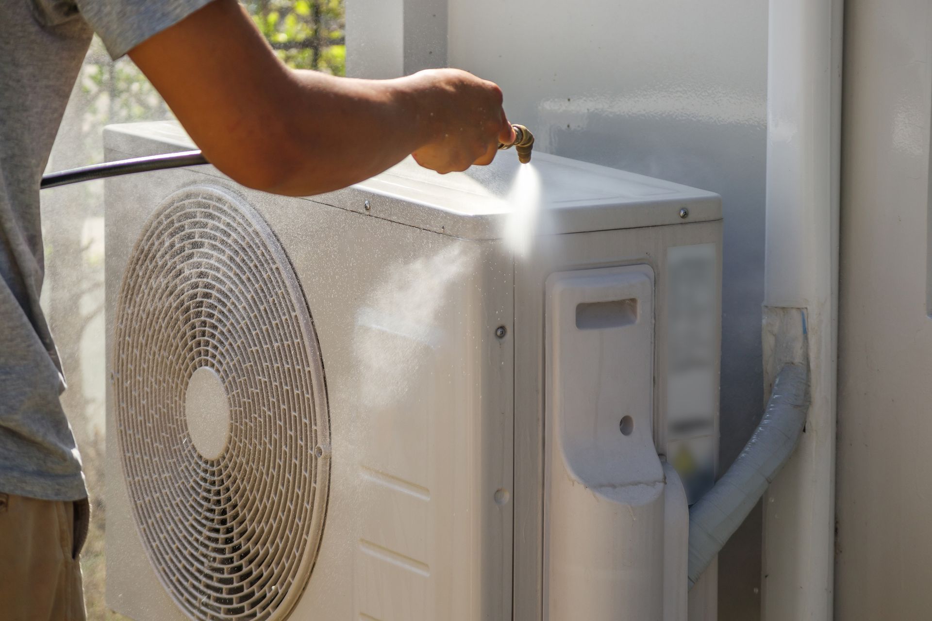 Hand cleaning an outdoor air conditioner unit with a spray bottle