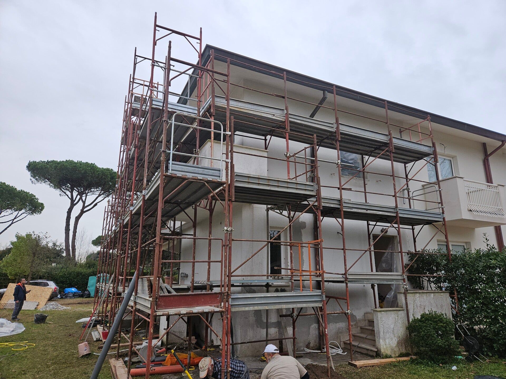 Casa a due piani in costruzione con impalcature e operai all'esterno.