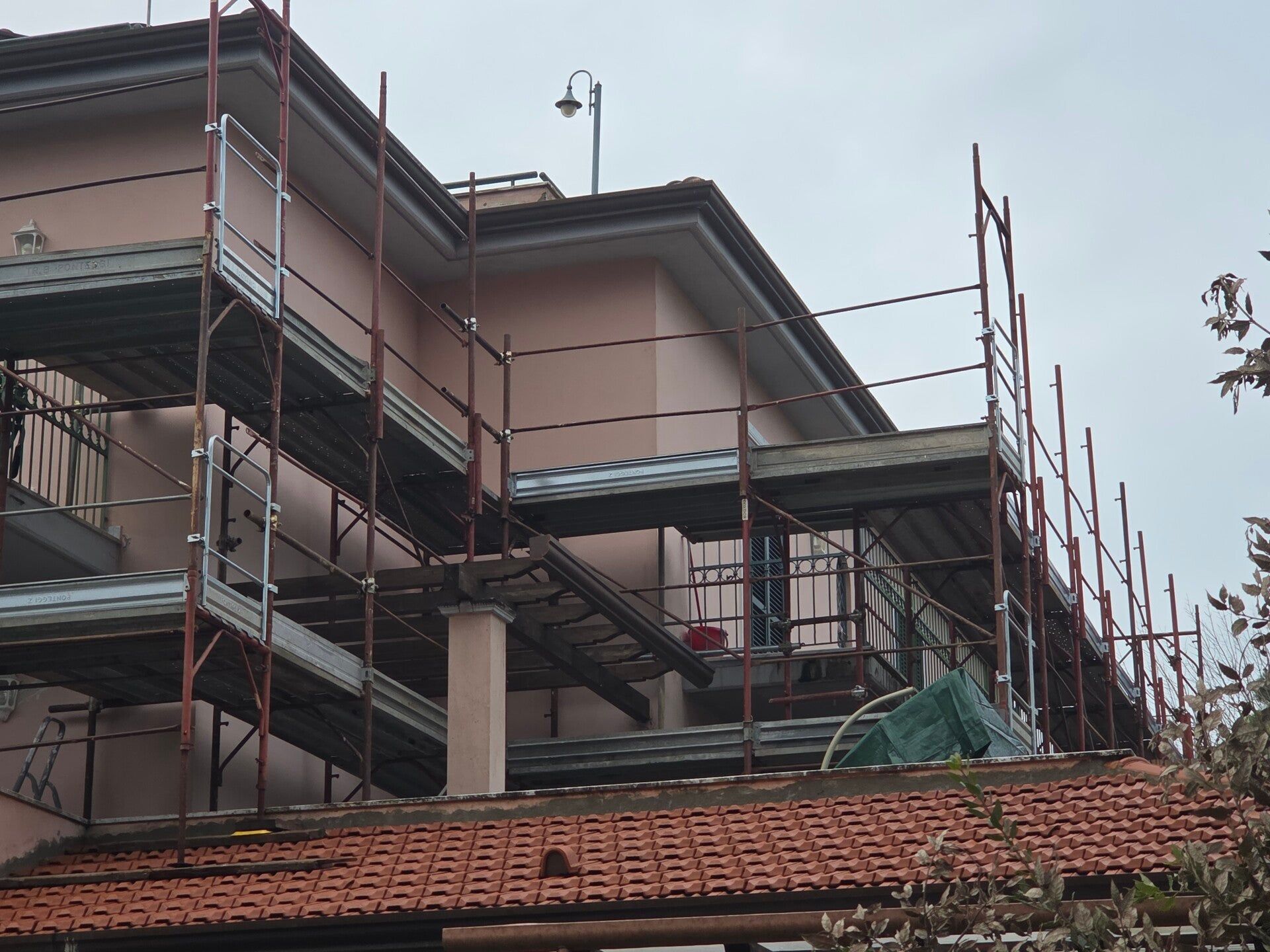 Casa in costruzione con impalcature intorno all'esterno e tetto di tegole rosse sul davanti.